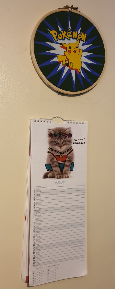 A picture in an embroidery hoop and a calendar hanging on a wall