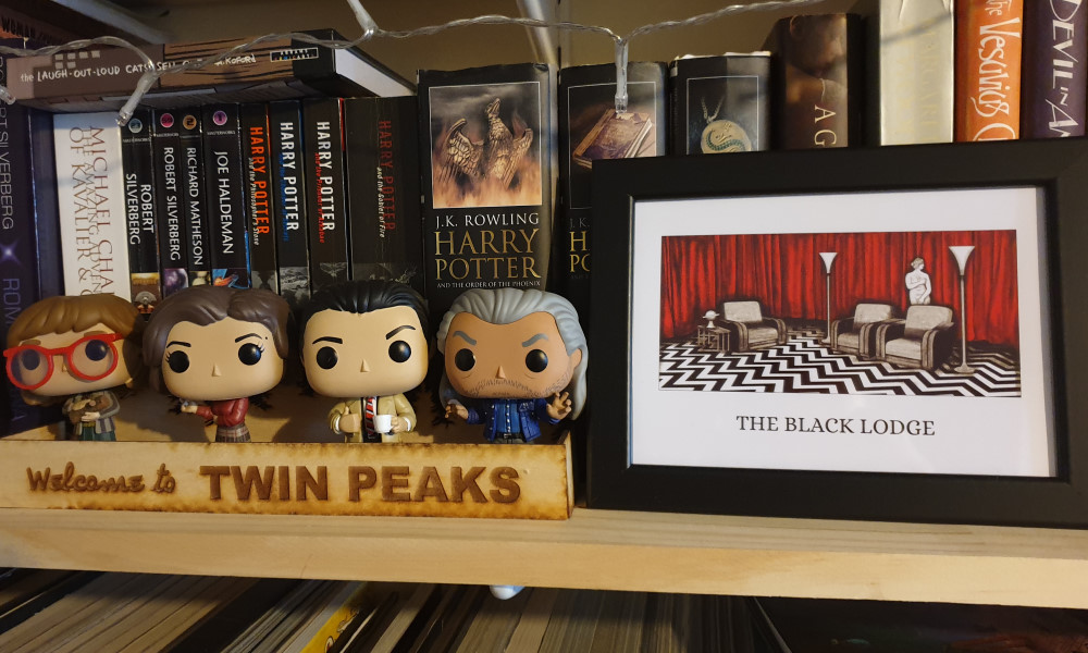 Four Twin Peaks Funko Pops next to a picture of the Black Lodge