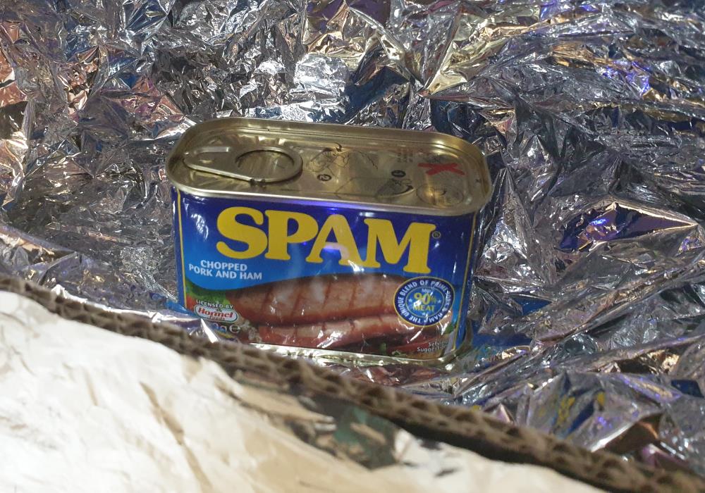 A small can of Spam inside a box covered with silver Mylar