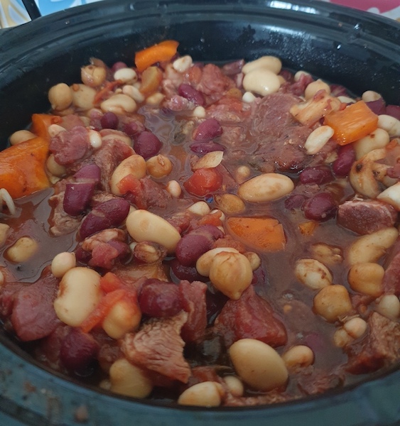 A slow cooker bowl filled with cooking chilli